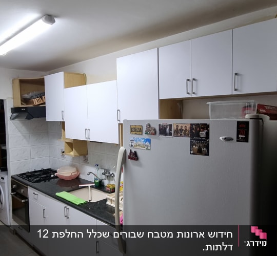 מטבח עם מקרר, ארונות לבנים וכיריים גז